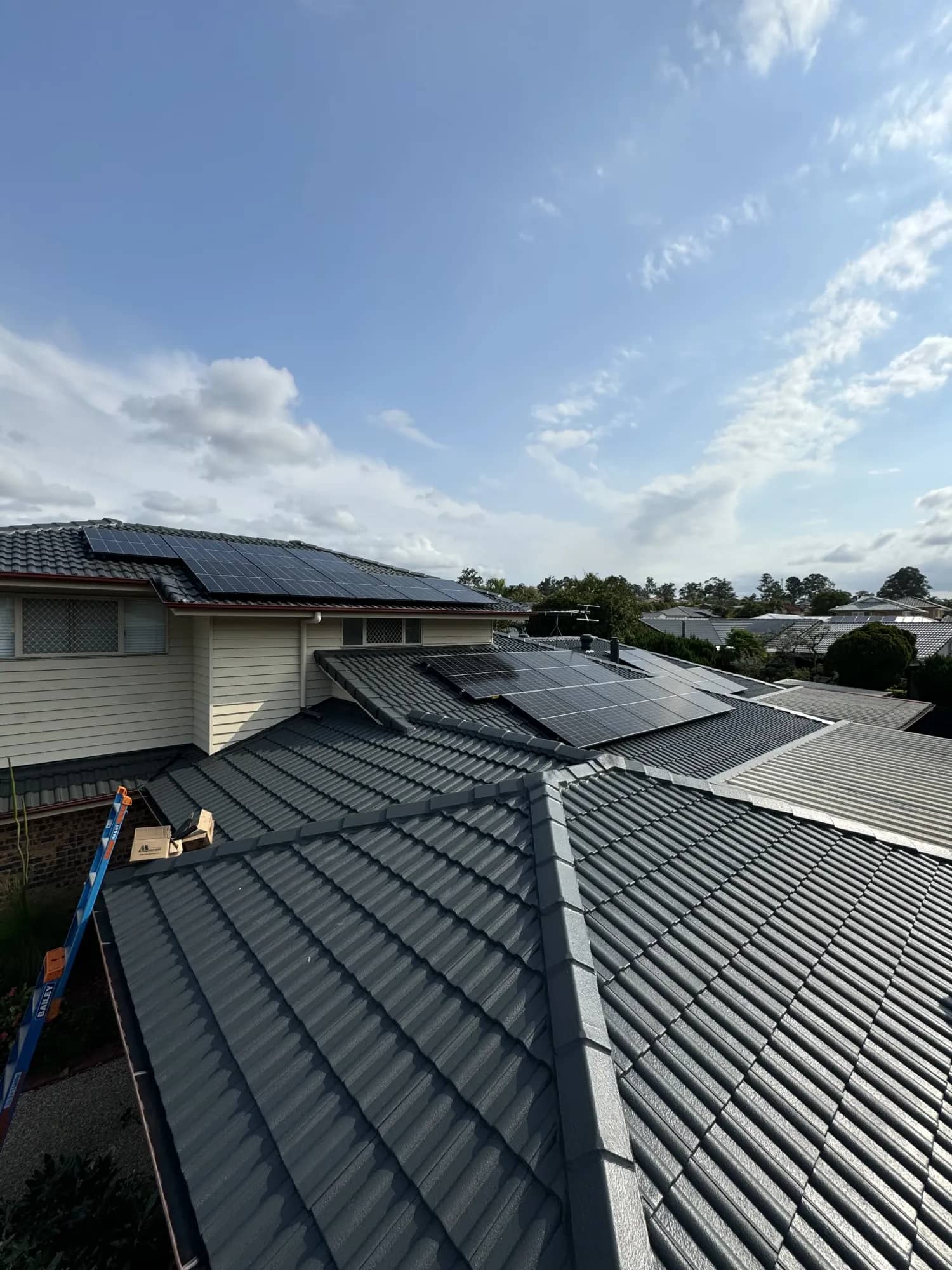Solar panels on a tiled roof, with a ladder against the eaves